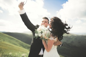 Just married couple on top of the mountain taking selfie picture.