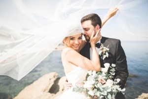 Happy and romantic scene of just married young wedding couple posing on beautiful beach.