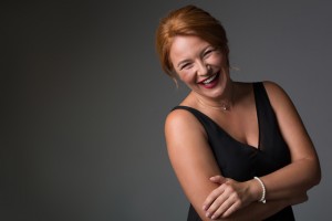 Waist up portrait of happy middle-aged woman standing in elegant black dress. She is looking at camera and laughing. Isolated and copy space