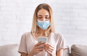Girl in protective mask reads news at smartphone about coronavirus quarantined